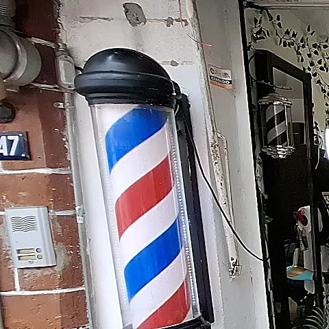 Poste de barbero de rayas rojas, blancas y azules en la fachada, junto al número 47